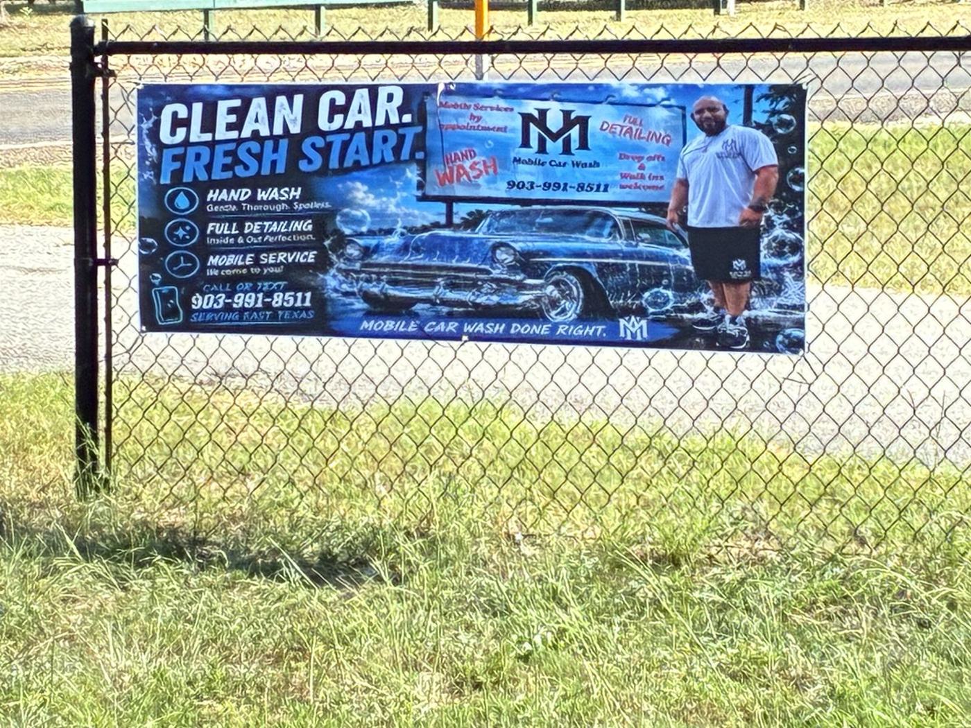 MH Mobile Car Wash banner on a fence